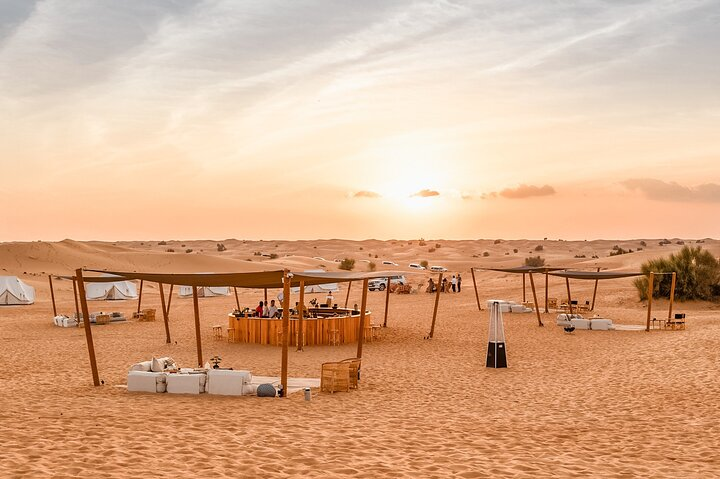 Experience the serene beauty of the desert at sunset where luxury dining meets captivating activities all set against the stunning backdrop of endless dunes.